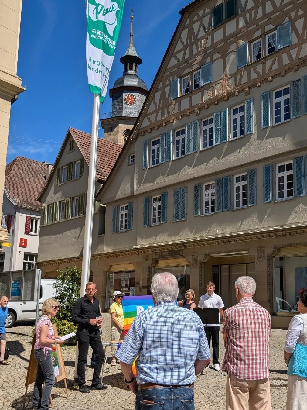 Oberbürgermeister Skrzypek und die Friedensgruppe Kleinglattbachhissen die Fahne am Rathaus.